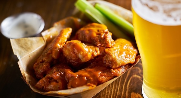beer and hot buffalo chicken wings in tray with celery