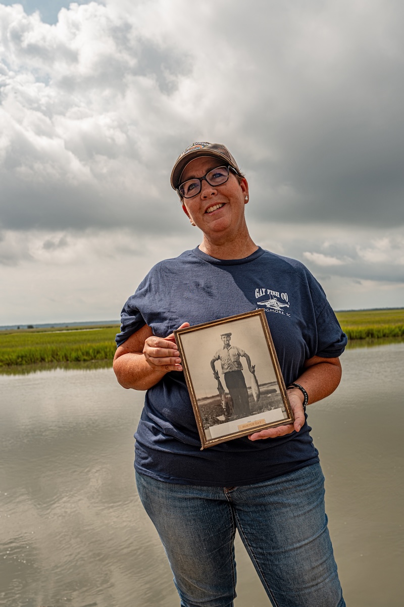 Cyndy Carr of Gay Fish Company holding a photograph of her grandfather, Lowcountry shrimper John H. “Buster” Gay.