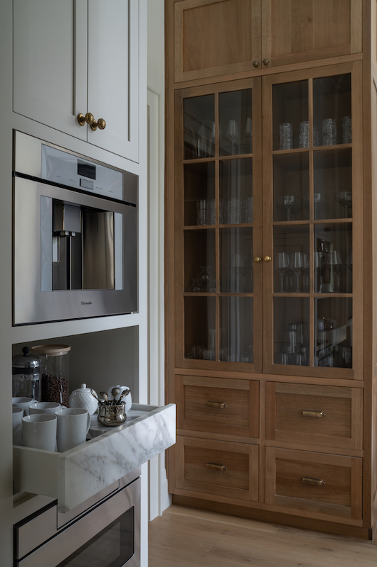 Back galley kitchen with glass paneled cabinetry by Court Atkins Group