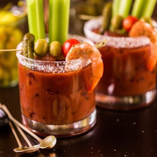 Classic Bloody Mary garnished with celery, olives, a gherkin, cherry tomato and seasoned cocktail shrimp.