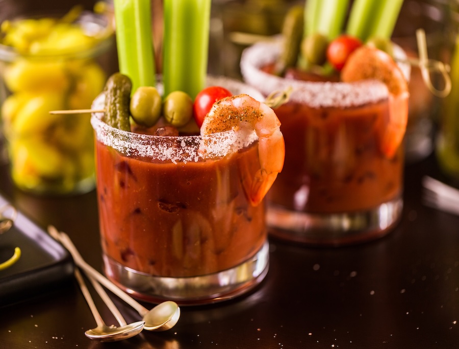 Classic Bloody Mary garnished with celery, olives, a gherkin, cherry tomato and seasoned cocktail shrimp.