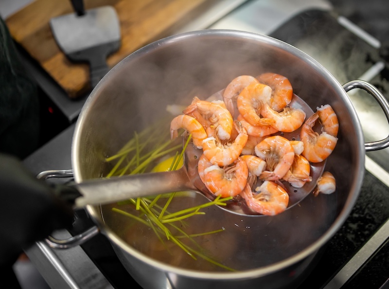Shell-on shrimp cooked in seasoned water using residual heat to prevent overcooking.
