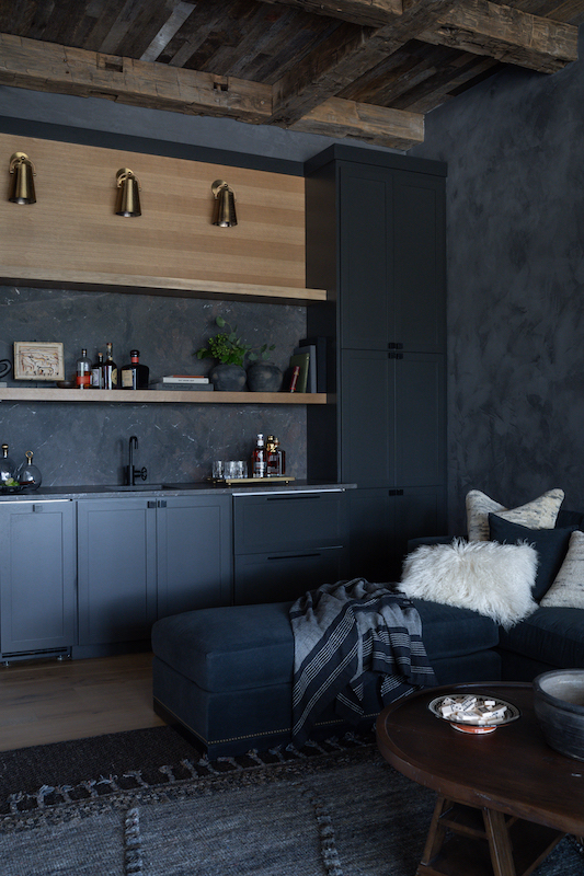 Dark lounge with sectional couch, oak cabinetry and dramatic, monochrome palette by Court Atkins Group
