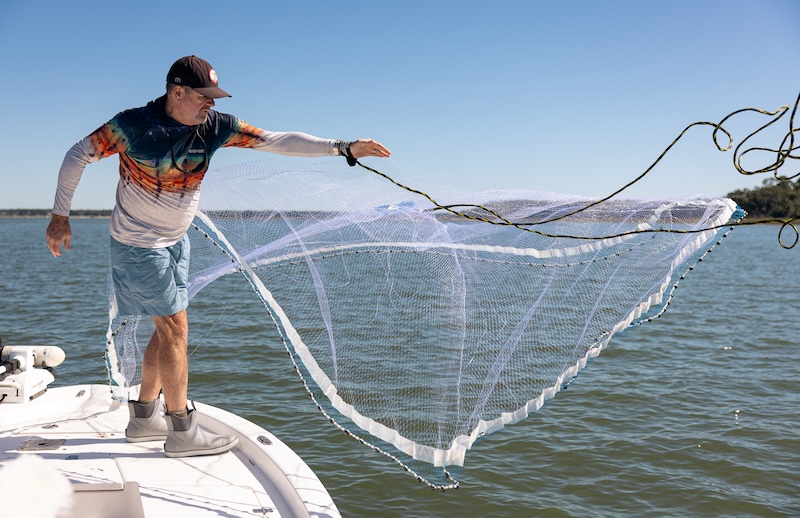 A person throwing a cast net from a boat while shrimping near Hilton Head Island.