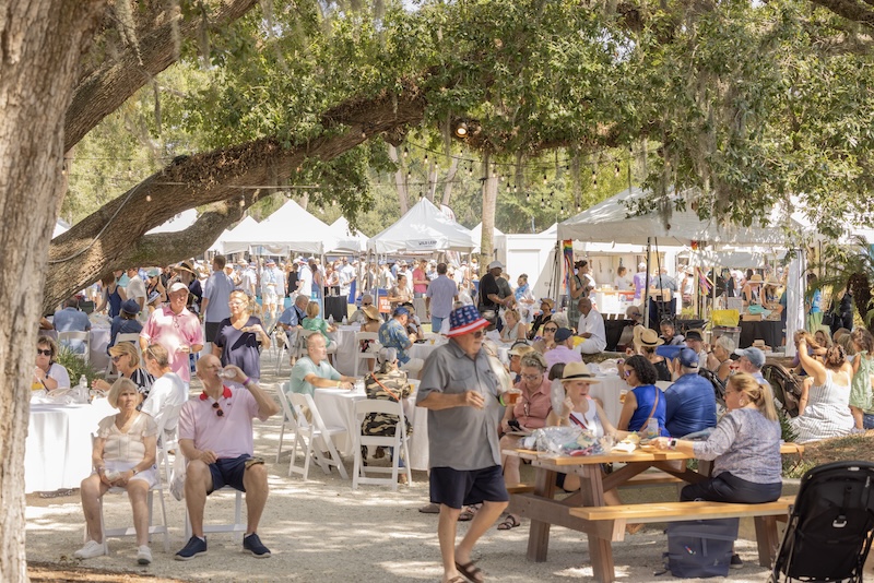 Crowds enjoying a Lowcountry shrimp and seafood festival under live oak trees.