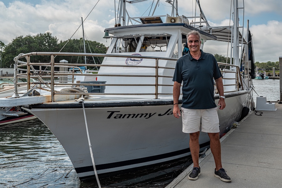 Vagabond Cruise owner Keith Walston standing beside the Tammy Jane shrimp boat on Hilton Head Island.