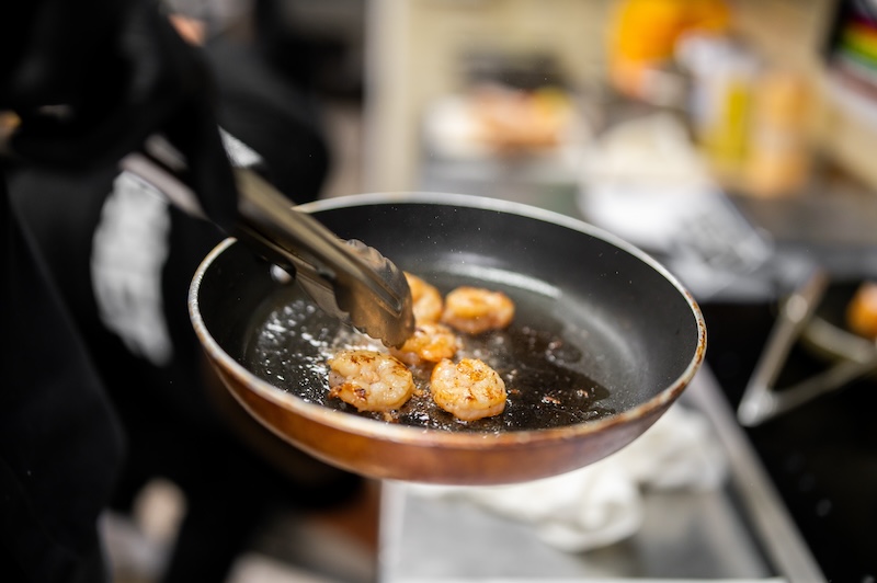 Shrimp searing in a hot skillet with butter or oil for quick browning.