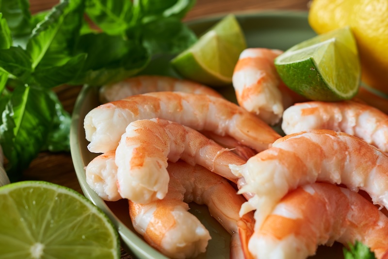 Cooked shrimp with fresh lime, a high-protein seafood option with very little saturated fat.