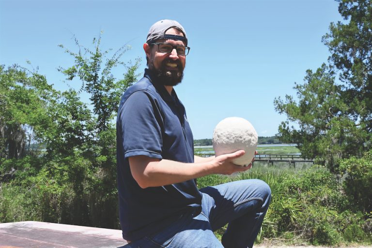 USCB marine biology professor Dr. Mercer Brugler holds a massive stony coral on the university's Beaufort campus
