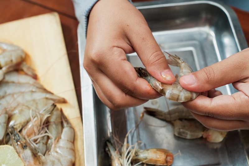 Shrimp being peeled with the shells saved to make homemade seafood stock.