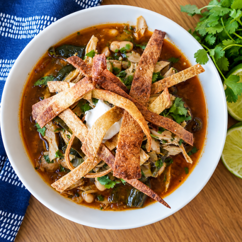 White chicken chili topped with sour cream, cilantro and crispy tortilla strips with fresh lime alongside