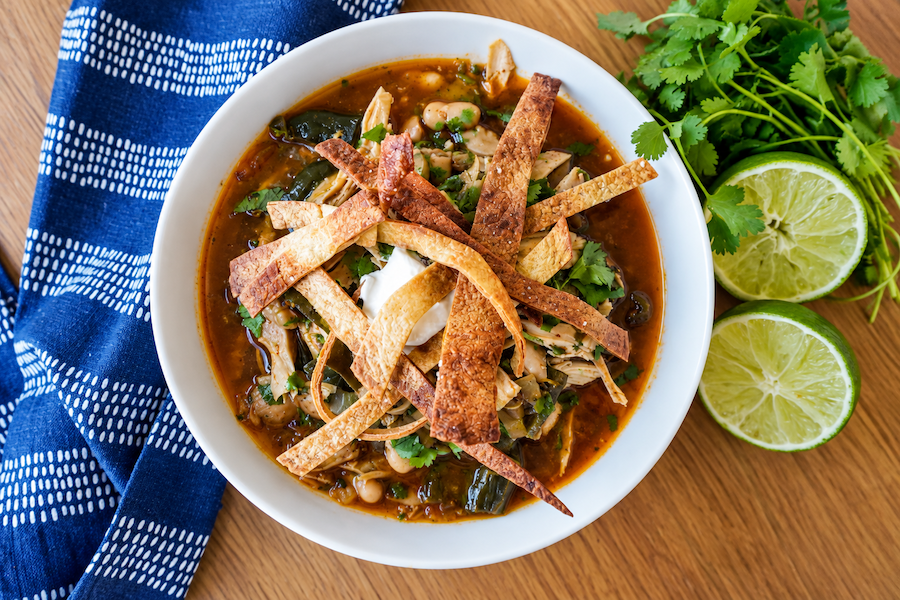 White chicken chili topped with sour cream, cilantro and crispy tortilla strips with fresh lime alongside