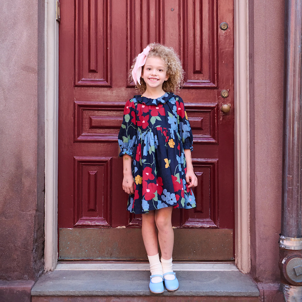 Young girl wearing a navy dress with an oversized colorful floral print