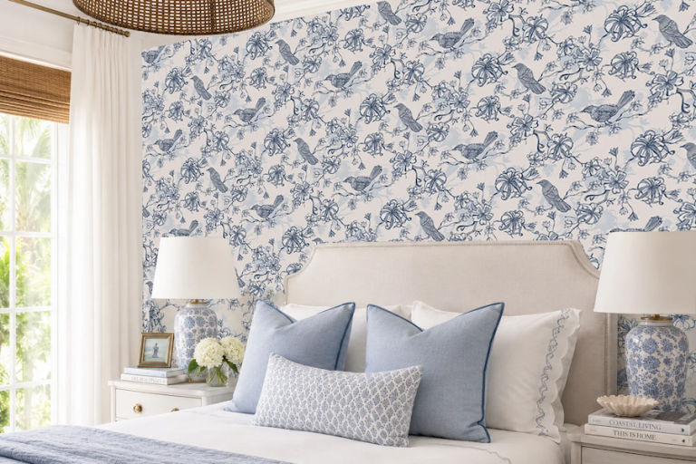 Bedroom with blue-and-white botanical wallpaper behind an upholstered bed with blue accent pillows