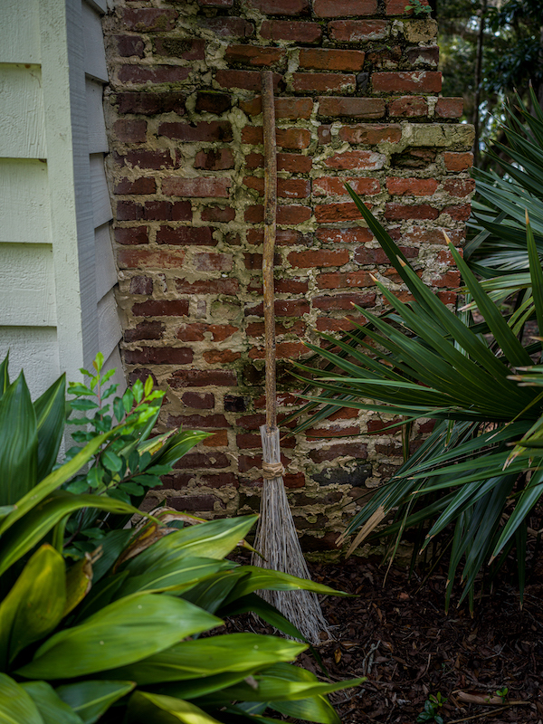 Broom resting against a brick wall beside a home