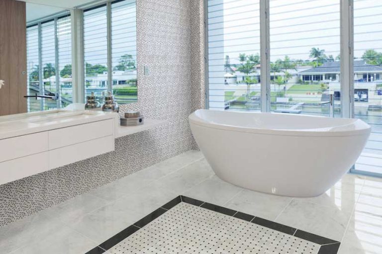 Coastal bathroom with patterned flooring, large-format tile, textured walls and a freestanding white tub