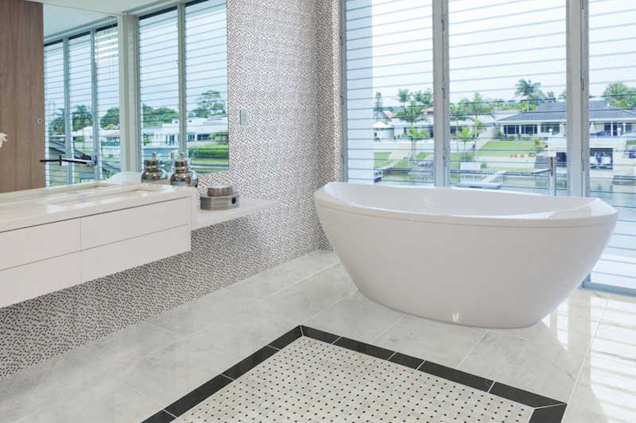Coastal bathroom with patterned flooring, large-format tile, textured walls and a freestanding white tub