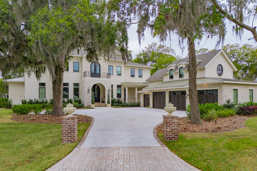 Two-story Colleton River home with an arched entry, mature trees and a curved driveway