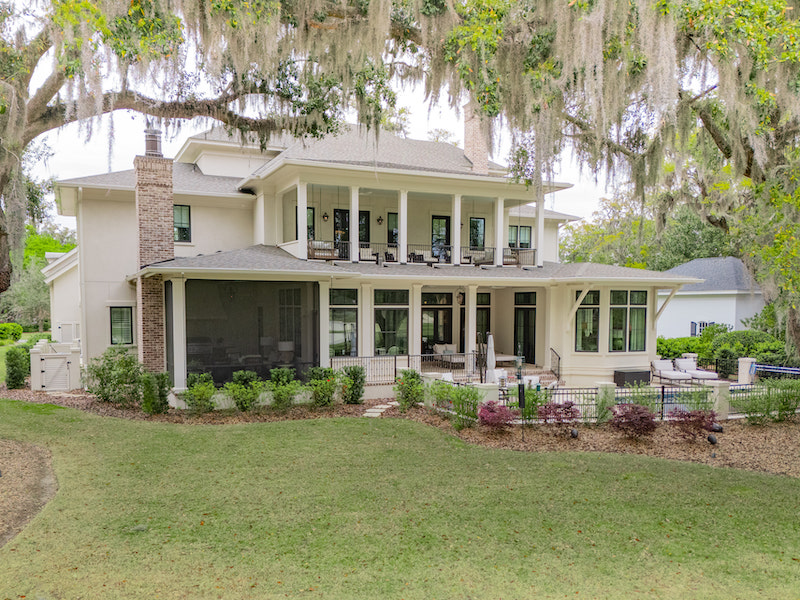 Rear of a two-story Colleton River home with stacked porches overlooking a spacious lawn