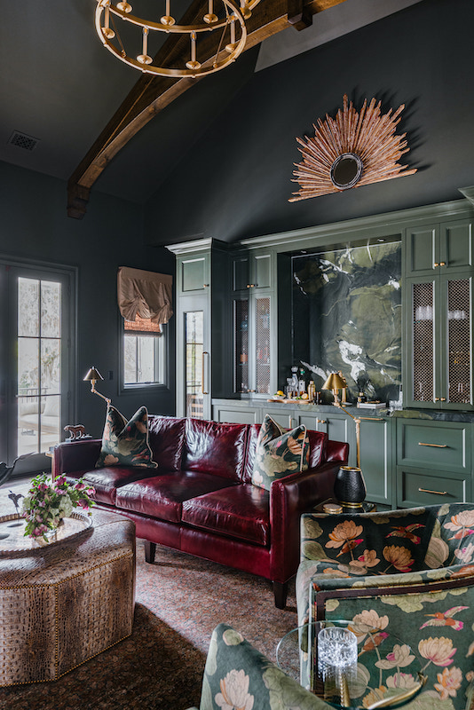 Dark-paneled sitting room with green cabinetry, a red leather sofa and floral accent chair