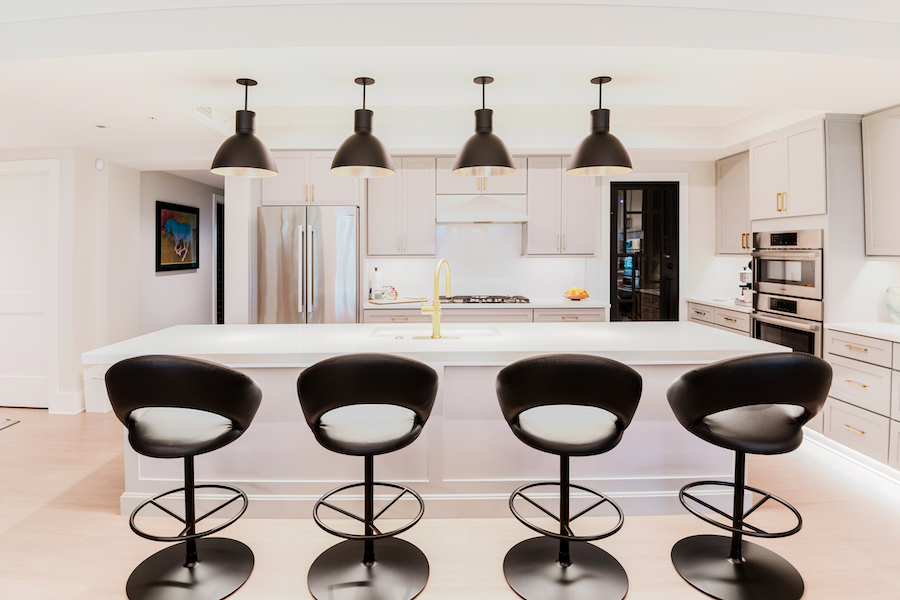 Bright kitchen with four pendant lights above a large island and under-cabinet lighting along the perimeter counters