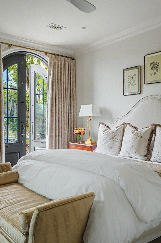 Bright bedroom with an upholstered bed, neutral furnishings and an arched glass door