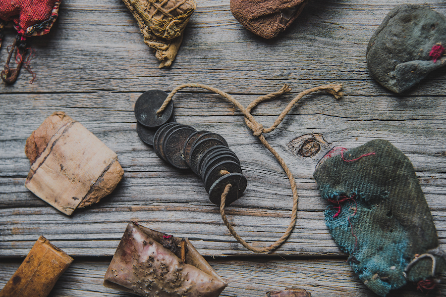 Rootwork charms, cloth bundles, roots and other objects arranged on a wooden surface