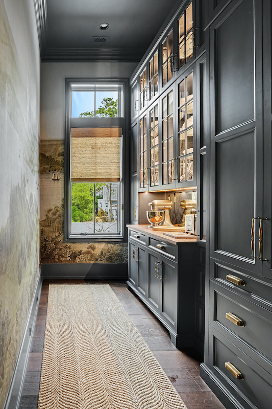 Narrow galley kitchen with navy cabinetry, patterned wall covering and a tall window