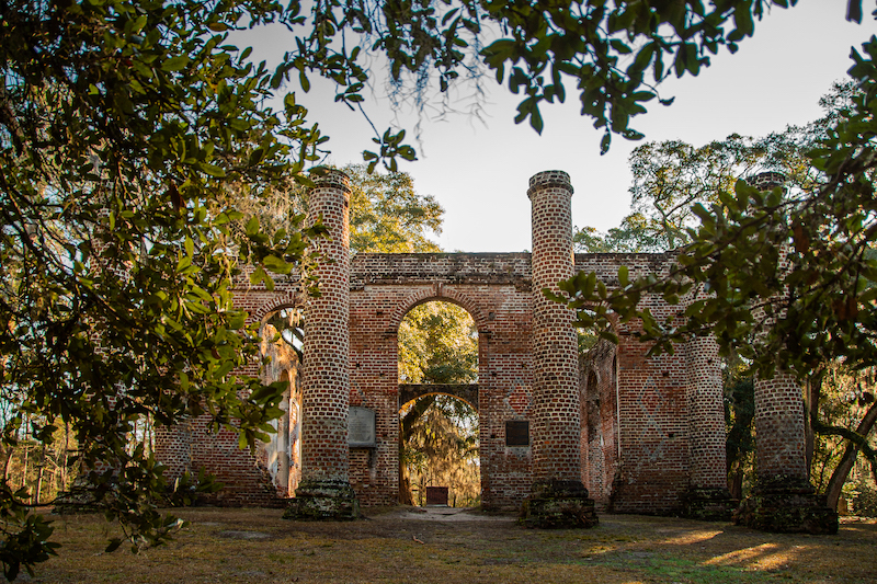 Brick walls and arched openings of Old Sheldon Church Ruins surrounded by trees
