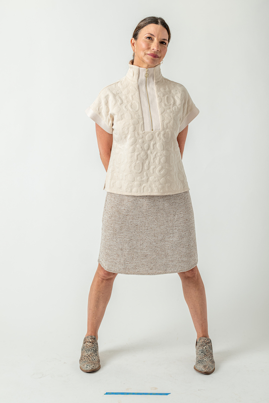 Woman wearing a textured white top with a tan skirt and leopard-print ankle boots