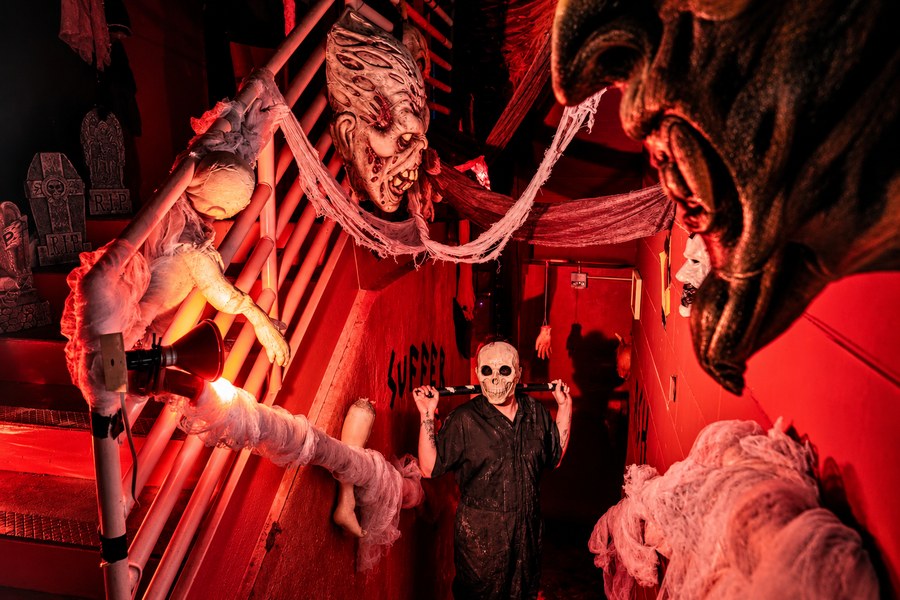 Costumed horror characters in a red-lit haunted attraction
