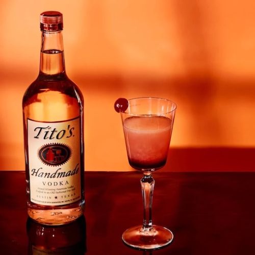 Red vodka cocktail with a dark pomegranate layer and cherry garnish