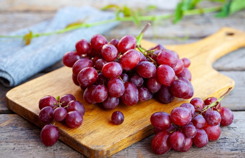 Bunches of red grapes on a wooden cutting board
