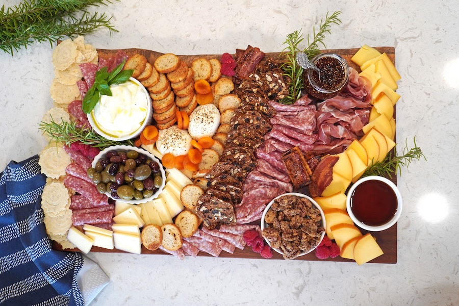 Charcuterie board with cured meats, cheeses, crackers, olives, fruit, candied pecans and whipped ricotta.