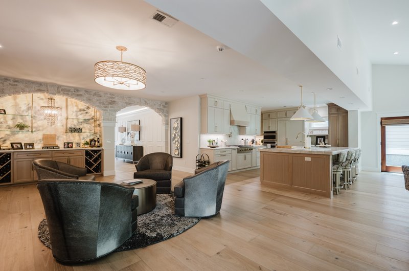 Open-concept living room with lounge chairs, stone bar and adjoining kitchen
