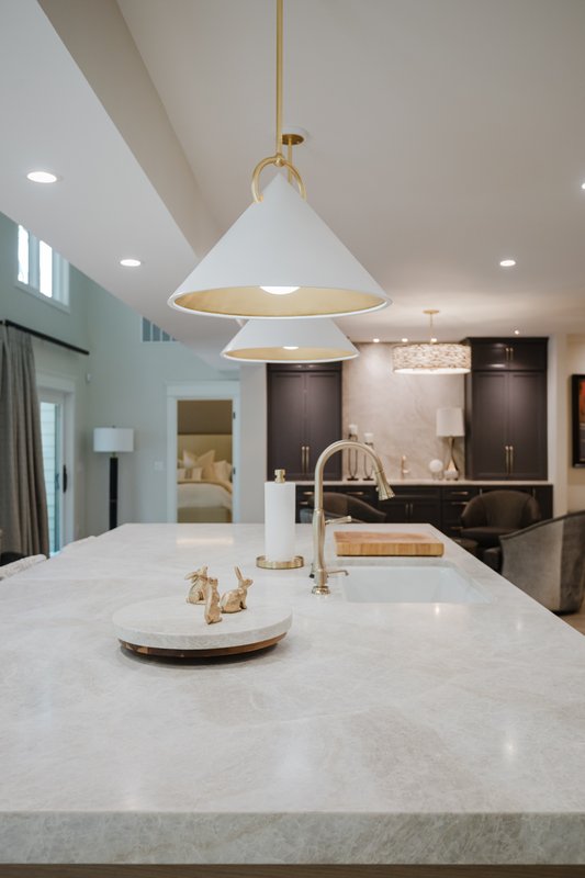 Stone kitchen island with brass faucet and white pendant light