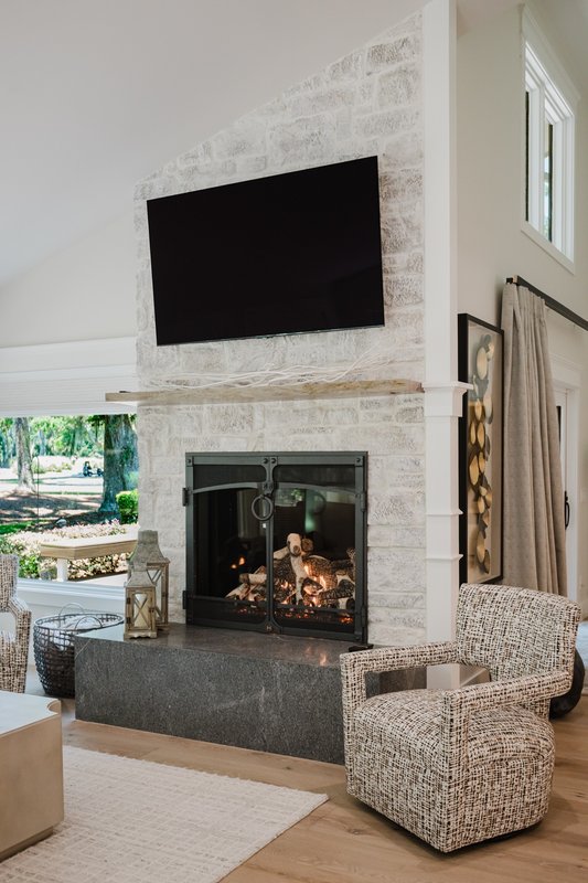 Stone fireplace with television above and two upholstered armchairs