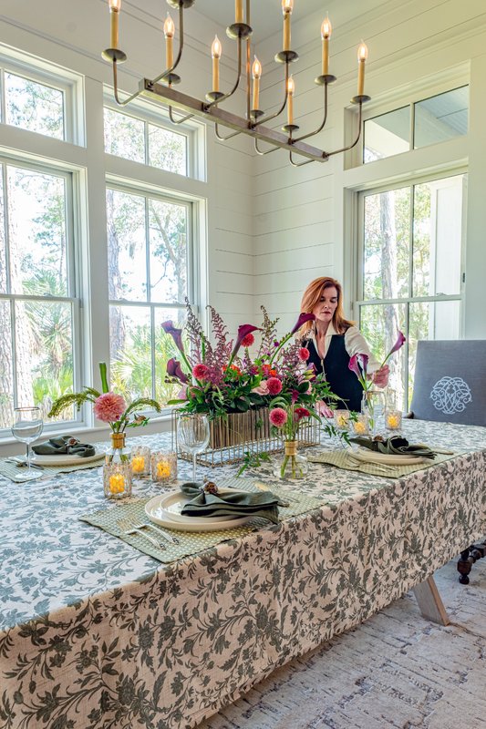 Floral designer Kim Epley beside a dining table decorated with colorful flowers and patterned linens