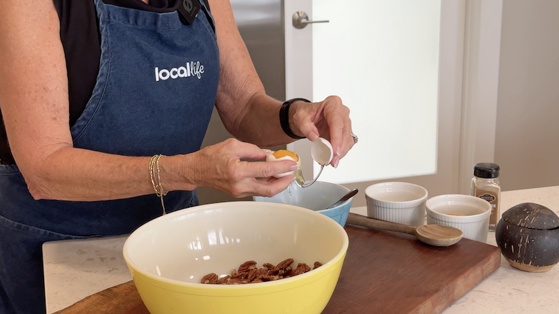 Hands separating an egg over a mixing bowl while preparing ingredients.