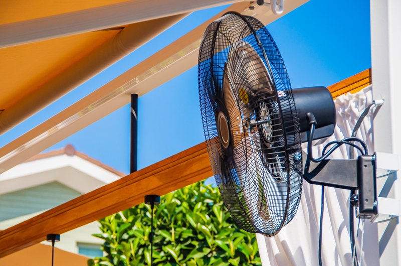 Fan mounted beneath a covered outdoor structure