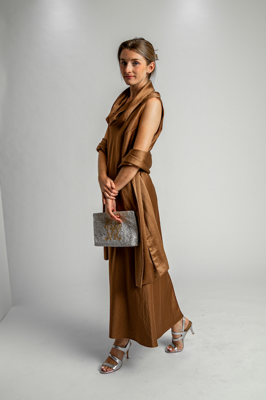 Woman wearing a bronze formal dress with a coordinating wrap, metallic heels and a clutch.