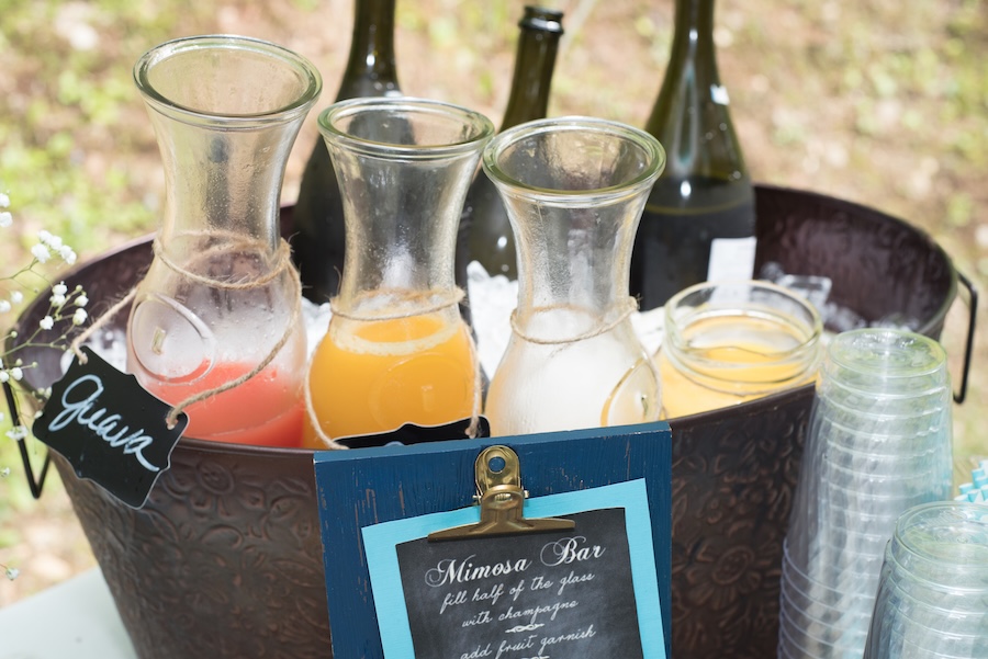 Mimosa bar with glass pitchers of fruit juices, chilled sparkling wine and cups arranged for guests.