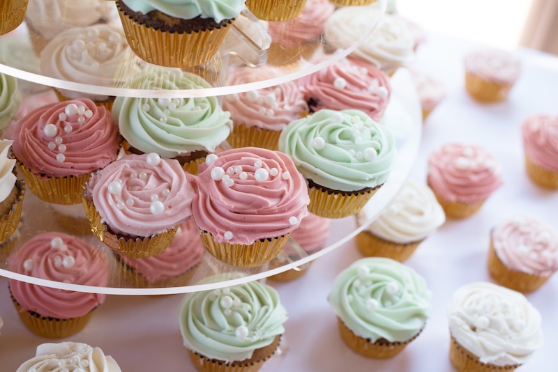 Assorted cupcakes with pastel-colored frosting arranged for a celebration.
