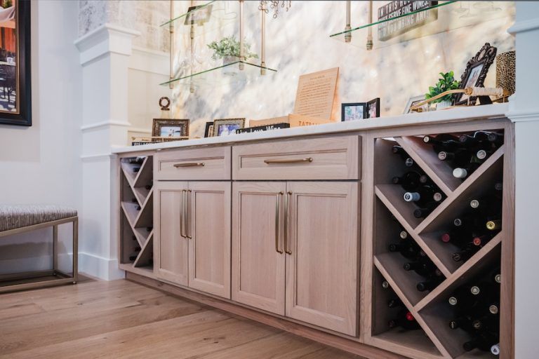 Custom wooden home bar cabinets with wine bottle storage beneath a quartzite countertop