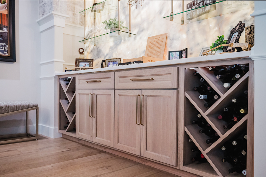 Custom wooden home bar cabinets with wine bottle storage beneath a quartzite countertop