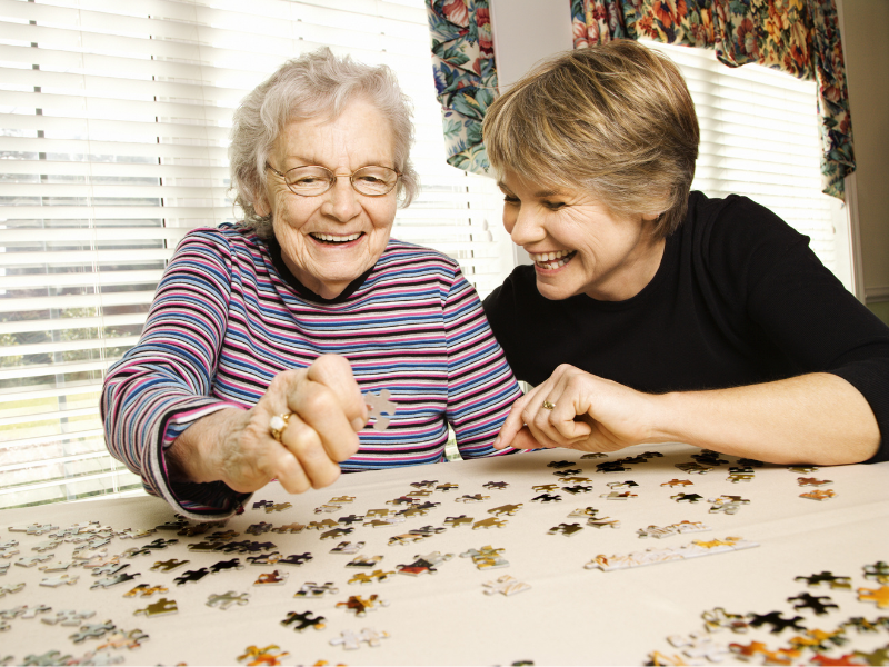 Elderly woman solving a puzzle with adult daughter