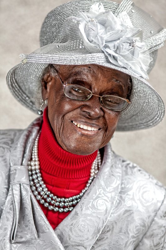 Ethel “Mother” Rivers smiling in a decorative silver hat and red top
