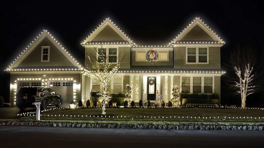 Lowcountry home decorated with warm white Christmas lights along the roofline, trees and front entrance.