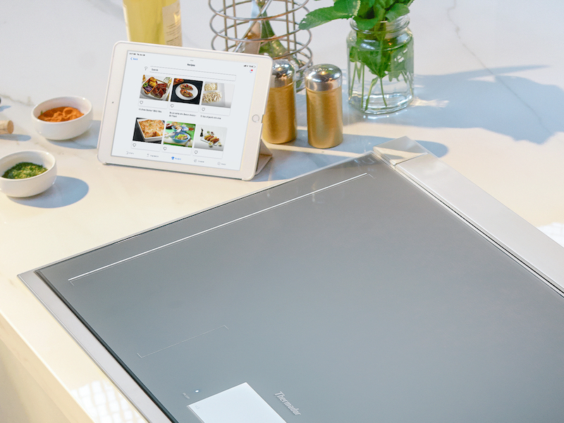 Smooth induction cooktop in a modern kitchen beside a digital cooking display