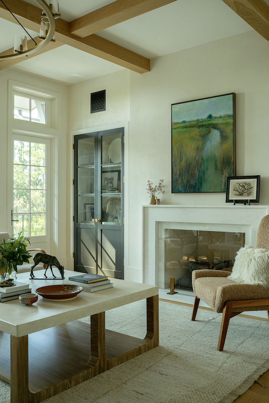 Palmetto Bluff living room with marsh landscape painting, marble fireplace, wood beams, bronze deer sculpture and textured furnishings